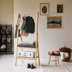 a white room with clothes hanging on the rack and other items sitting on the floor