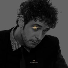 a man with curly hair and a cross on his forehead is staring at the camera