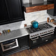 a stove top oven sitting inside of a kitchen next to black cabinets and counter tops