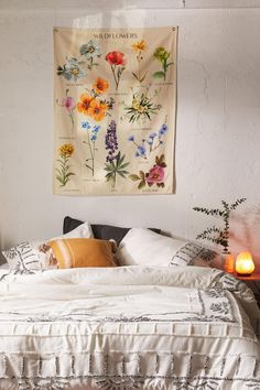 a bed with white sheets and pillows in front of a wall hanging on the wall