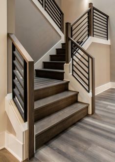 a staircase with wooden handrails and metal railing on the bottom floor in a home