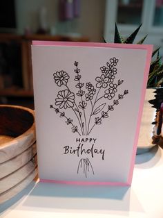 a happy birthday card sitting on top of a table next to a potted plant