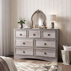 a bedroom with a bed, dresser and mirror on it's side table in front of a window