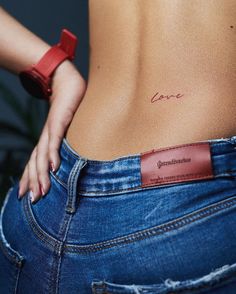 a woman's stomach with the word love tattooed on her lower back and side