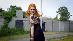 a woman with red hair is posing for a photo in front of a street sign