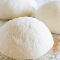 three uncooked doughnuts sitting on top of a floured countertop