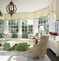 a living room filled with lots of furniture next to a window covered in white curtains