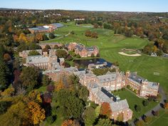 an aerial view of a large building in the middle of trees with fall foliage around it