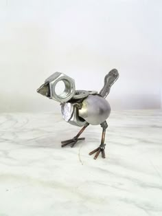 a small metal bird sitting on top of a white counter next to a bottle opener