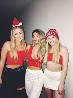 three young women in red and white outfits posing for a photo with one woman wearing a santa hat