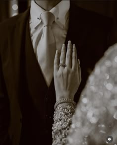 a close up of a person wearing a suit and tie with their hands clasped together