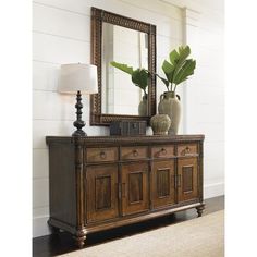 a wooden dresser sitting next to a lamp and a mirror on top of a wall