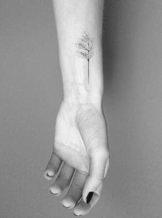 a woman's arm with a small tree tattoo on the left side of her wrist