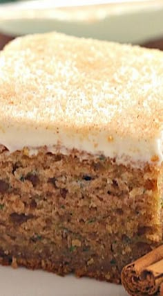 a close up of a slice of cake on a plate with cinnamon sticks next to it