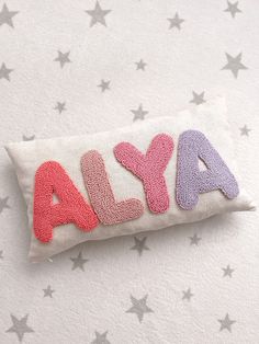 a pillow with the word aly spelled out in pink, purple, and blue