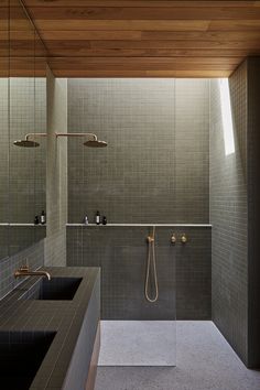 a bathroom with two sinks and a shower in the middle, surrounded by tiled walls