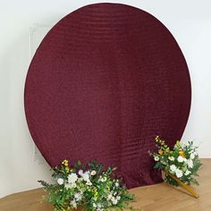 two vases filled with flowers sitting on top of a wooden table next to a round object