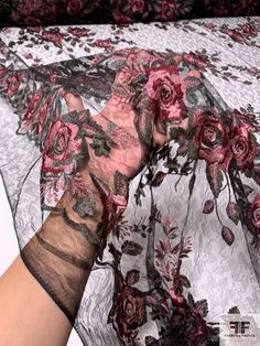 a woman's hand holding an umbrella with roses on it and lace over the top