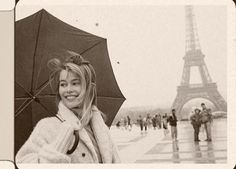 a woman holding an umbrella in front of the eiffel tower