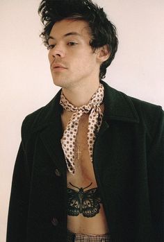 a man with no shirt wearing a black jacket and white polka dot bow tie on his chest