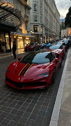 a row of red sports cars parked on the side of a street next to tall buildings