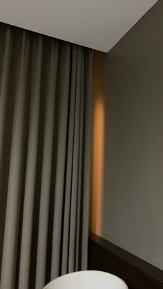 a bathroom with a large white bathtub next to a window covered in gray drapes