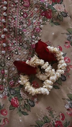 some flowers are laying on top of a floral print fabric with red and white roses