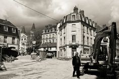 a man standing in the middle of a street next to a bulldozer and buildings