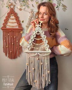 a woman is holding a piece of art that looks like a birdhouse with beads on it