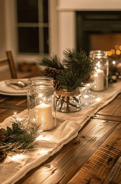 the table is set with candles, pine cones and evergreen branches in mason jar holders