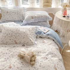 a bed with blue and white comforters next to a table with flowers on it