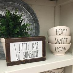 three bowls are sitting on a shelf next to a sign that says home sweet, a little rae of sunshinene