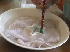 a person in a white bowl holding a star shaped toothbrush with sugar on it