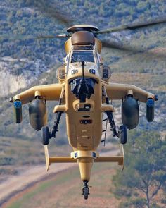 a yellow helicopter flying over a lush green hillside