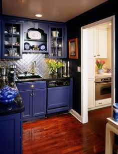 a kitchen with dark blue cabinets and wood flooring is pictured in this image from the doorway to the dining room