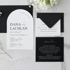 the black and white wedding stationery is laid out on top of the marble table