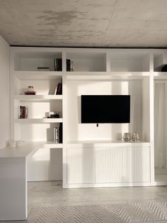 a living room with bookshelves and a flat screen tv mounted on the wall