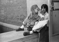 black and white photograph of two people sitting on a ledge