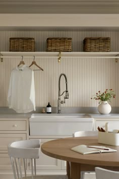 a kitchen with a table, sink and hanging clothes on the rack above it's counter