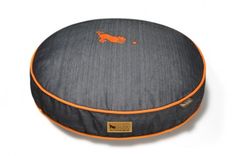 a round dog bed with an orange stripe on the front and bottom, sitting on a white background