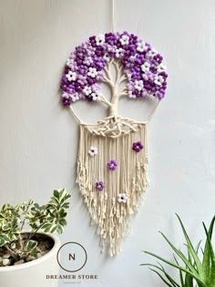 purple and white flowers are hanging on the wall next to a potted plant in front of it