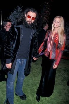 a man with long hair and sunglasses walking next to a woman