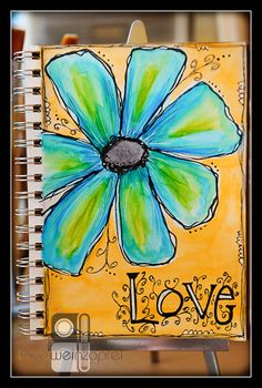 an art journal with the word love written on it and a blue flower in the middle