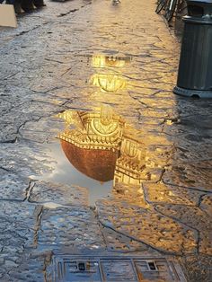 a reflection of a boat in a puddle on the ground next to a street light