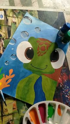 an art project with watercolors and paints on the table next to it is a frog