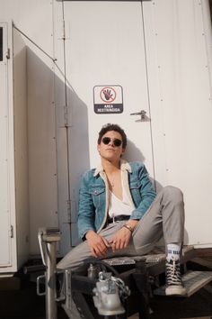 a man sitting on the back of a truck next to a white wall with a no parking sign