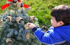 a young boy decorating a christmas tree with cones and pineconi on it