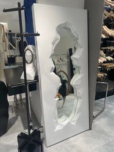 a mirror that is in the middle of a room with clothes on racks behind it