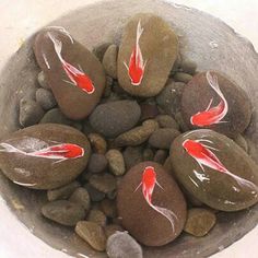 some rocks with red and white designs on them in a bowl filled with water stones