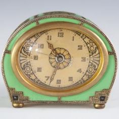 an antique green and gold clock on a white background